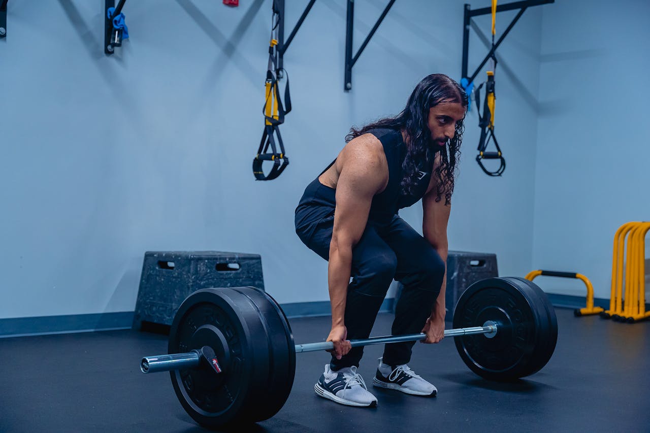 services-04 A man performing deadlifts in a gym, showcasing strength training and fitness routines.