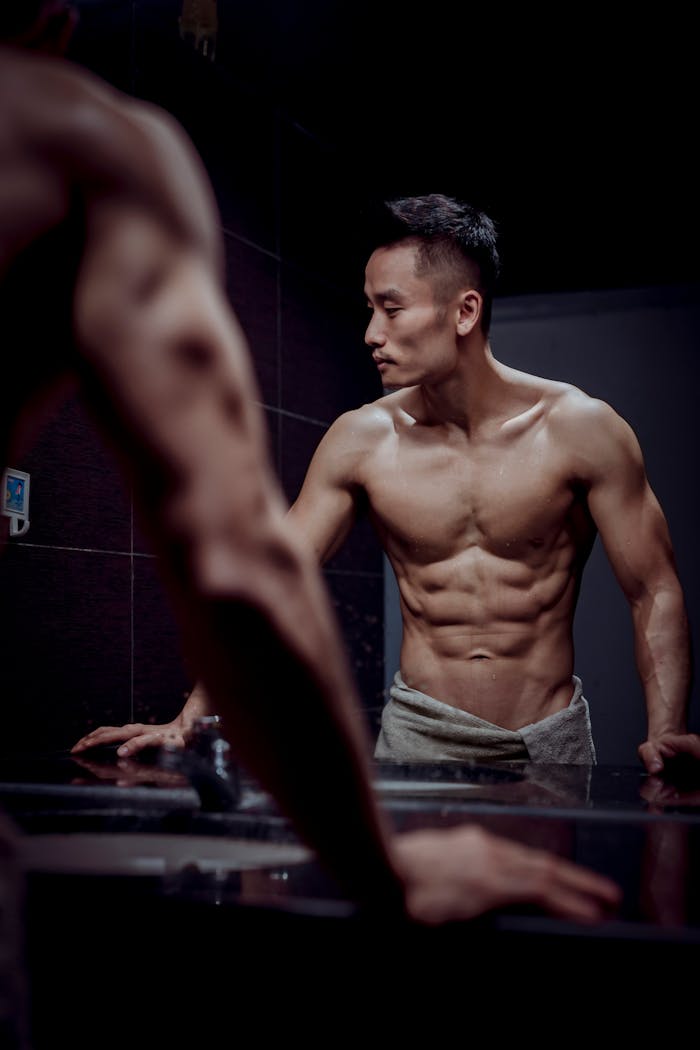 Muscular young man flexing in the mirror, showcasing fitness and strength.
